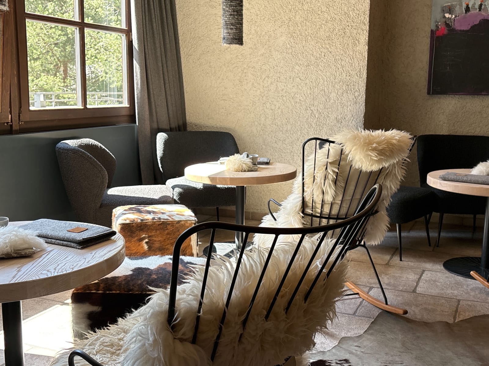 Lounge mit Korbsesseln, Schaffellen und runden Tischen auf Steinboden (Drohne/Übersicht) – MONTAFONLodge