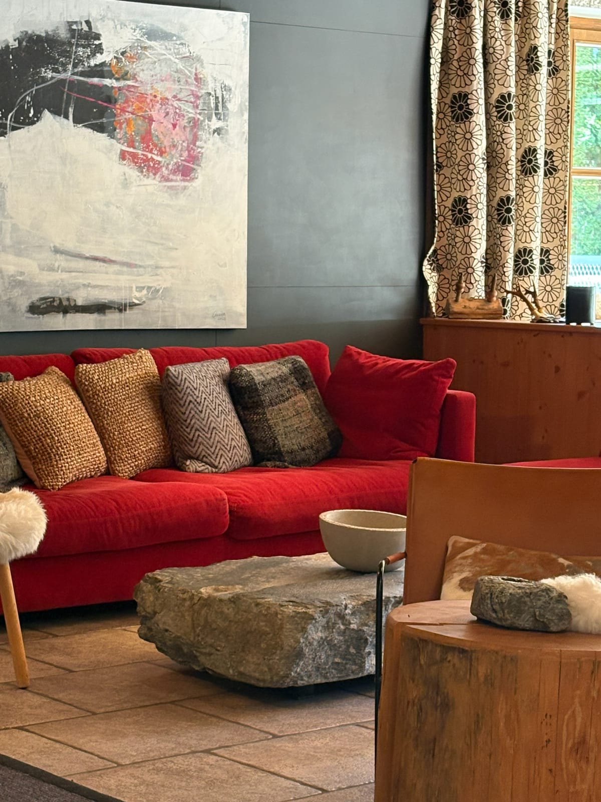 Rotes Sofa mit gemusterten Kissen, Wandbild und Vorhängen – MONTAFONLodge