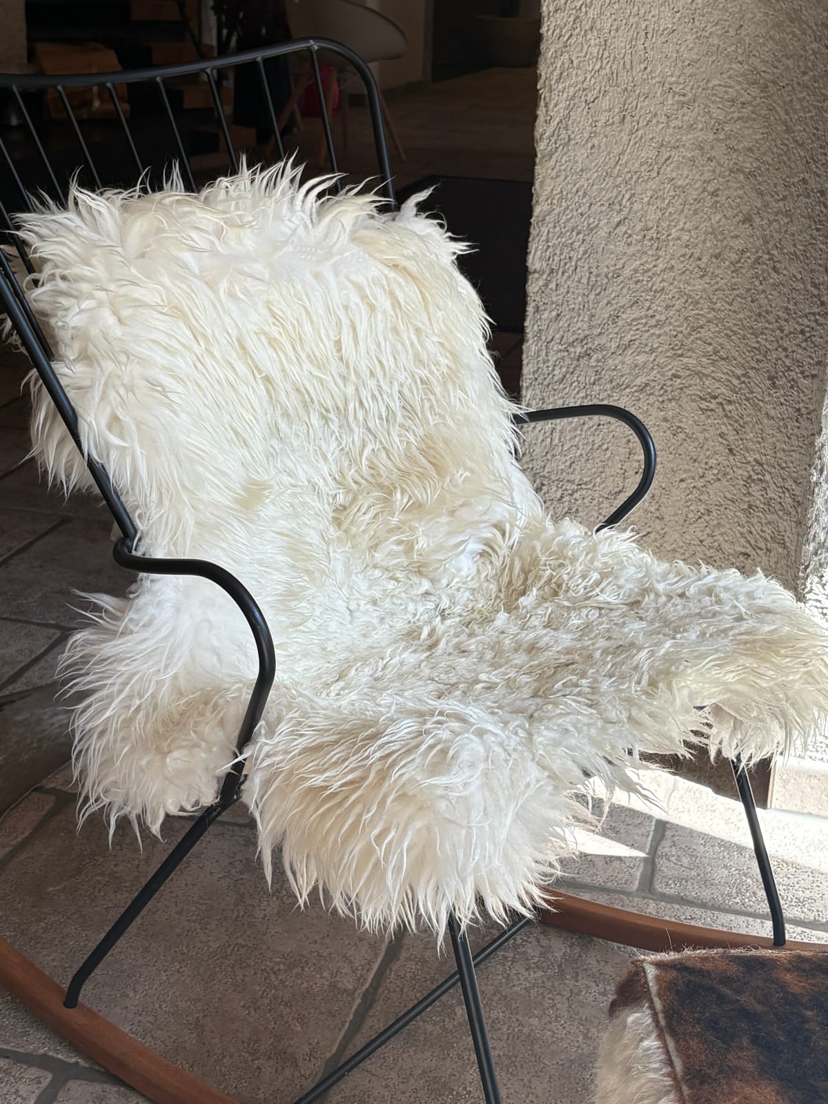 Sessel mit weißem Schaffell auf Steinboden, Detailaufnahme – MONTAFONLodge