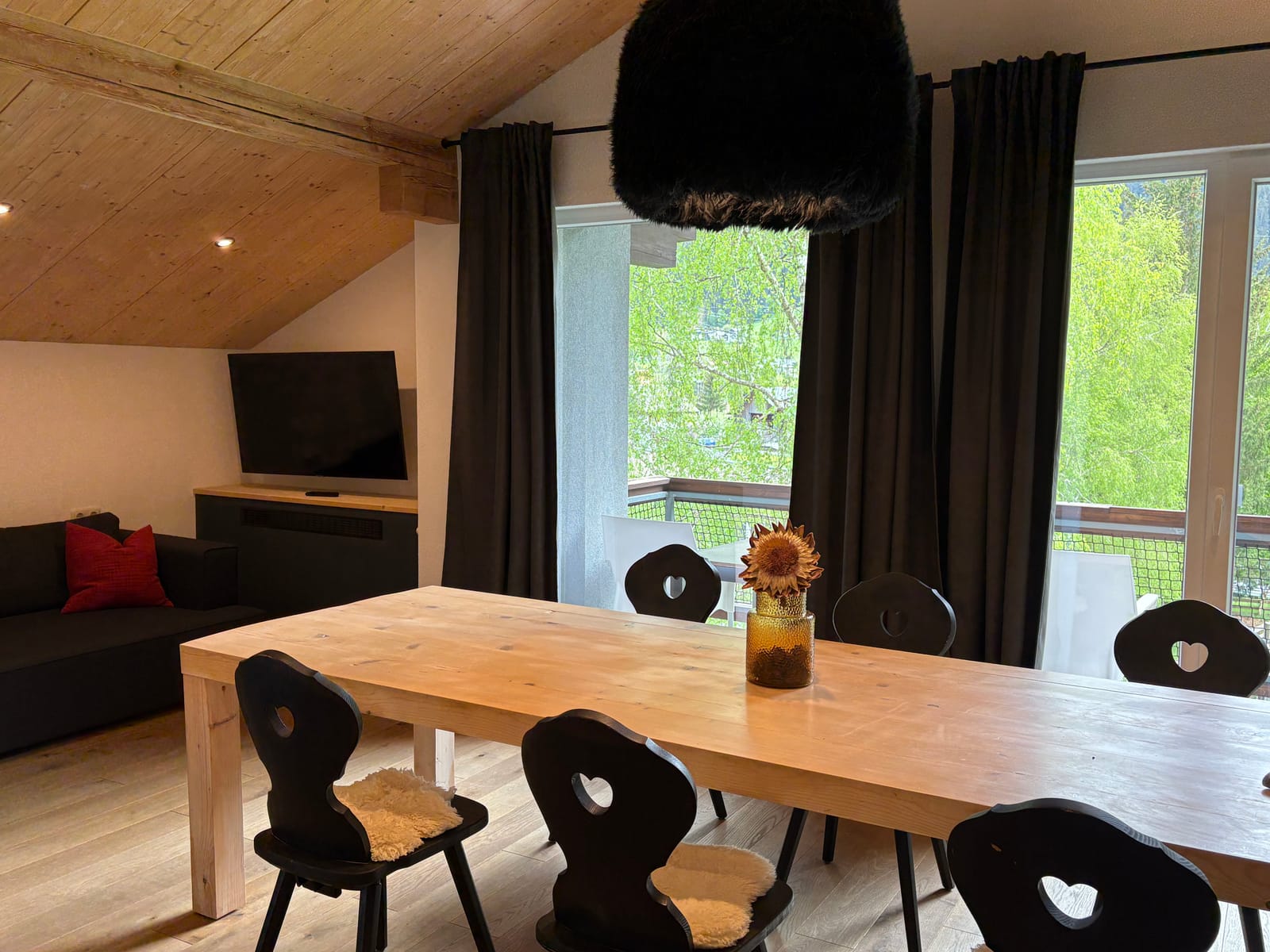 Essbereich mit langem Holztisch und schwarzen Stühlen am Fenster – MONTAFONLodge