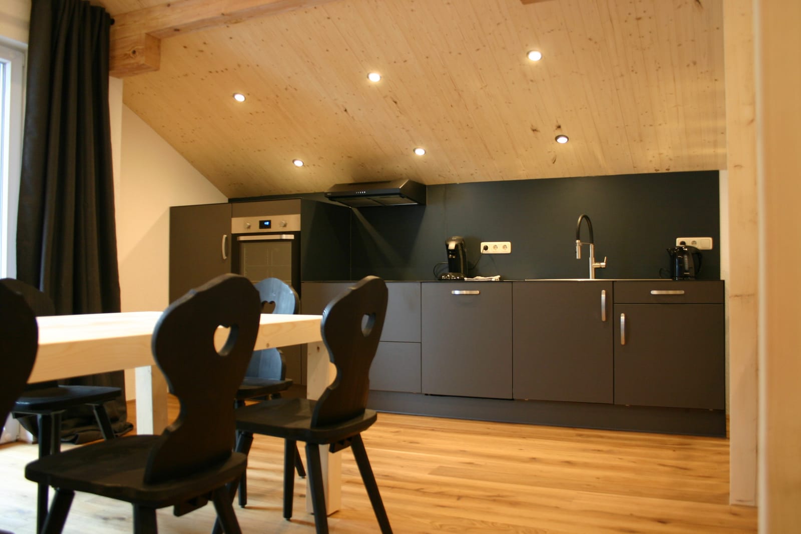 Chalet-Wohnküche mit Essplatz, dunkler Küchenzeile und Deckenspots – MONTAFONLodge
