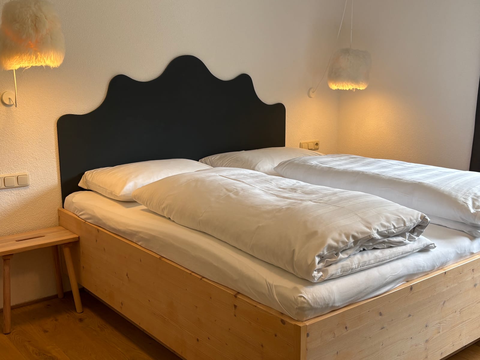 Doppelbett mit dunklem Kopfteil und Fellteppich – MONTAFONLodge