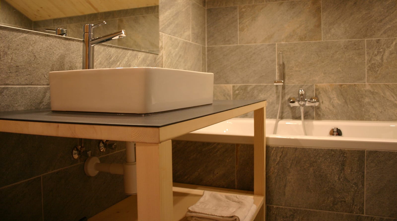 Bad mit Waschbecken und Badewanne, Steinfliesen – MONTAFONLodge