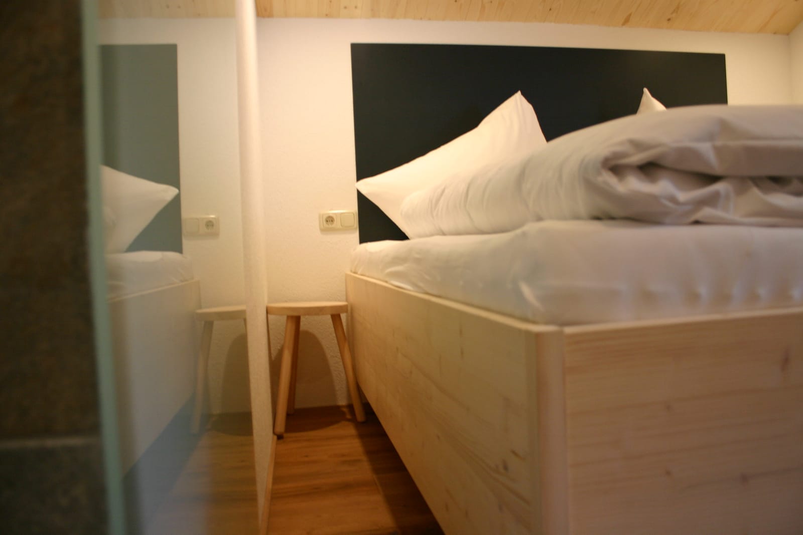 Doppelbett mit dunklem Kopfteil, Detailaufnahme des Bettbezugs – MONTAFONLodge