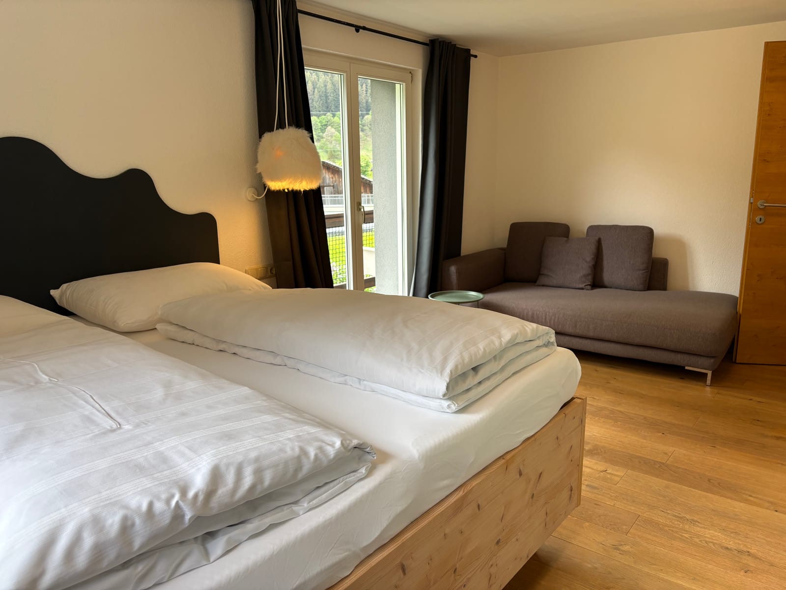 Doppelbett mit Blick zum Fenster und Sofa – MONTAFONLodge