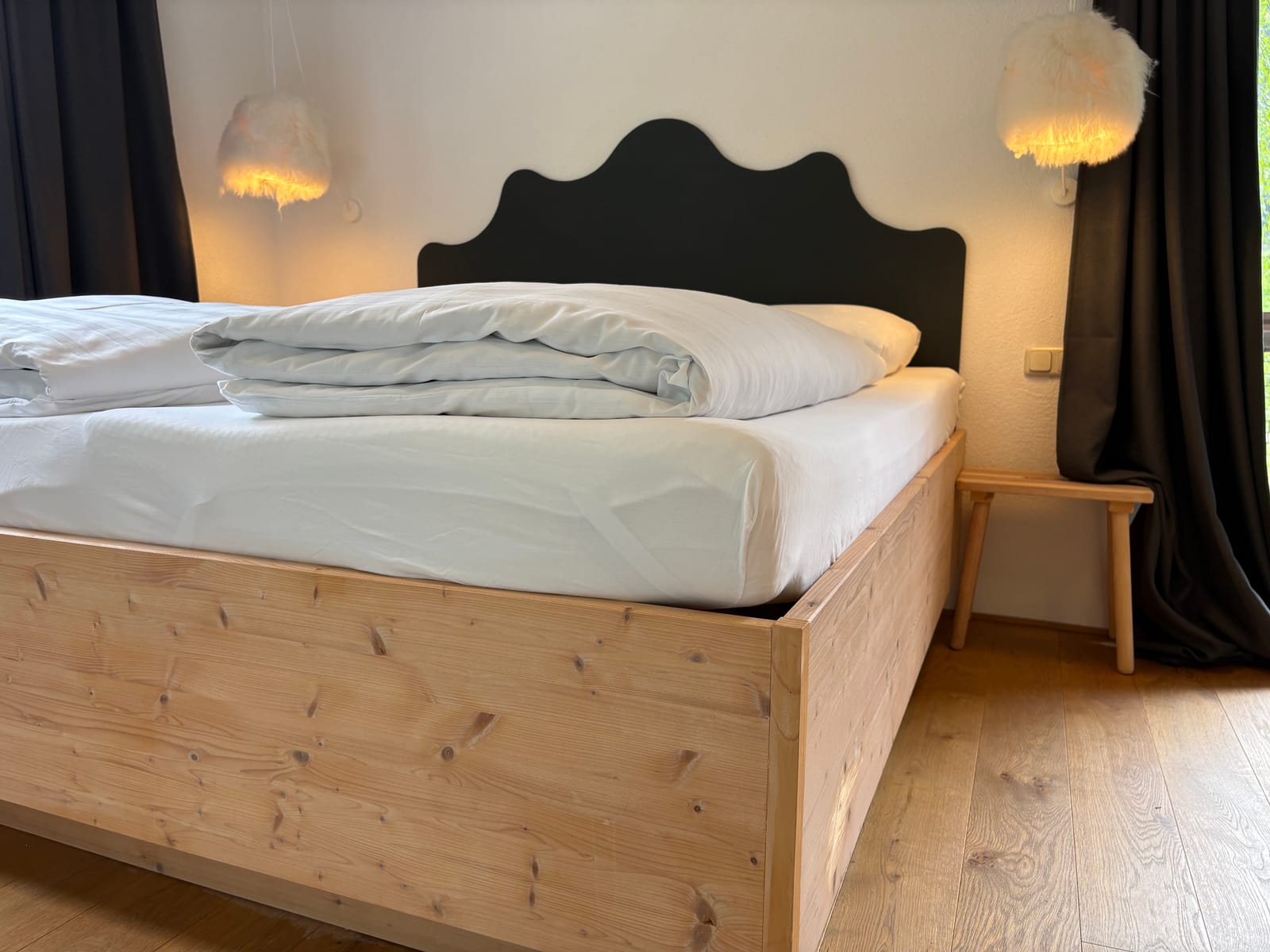 Doppelbett mit dunklem Kopfteil und Wandleuchten – MONTAFONLodge