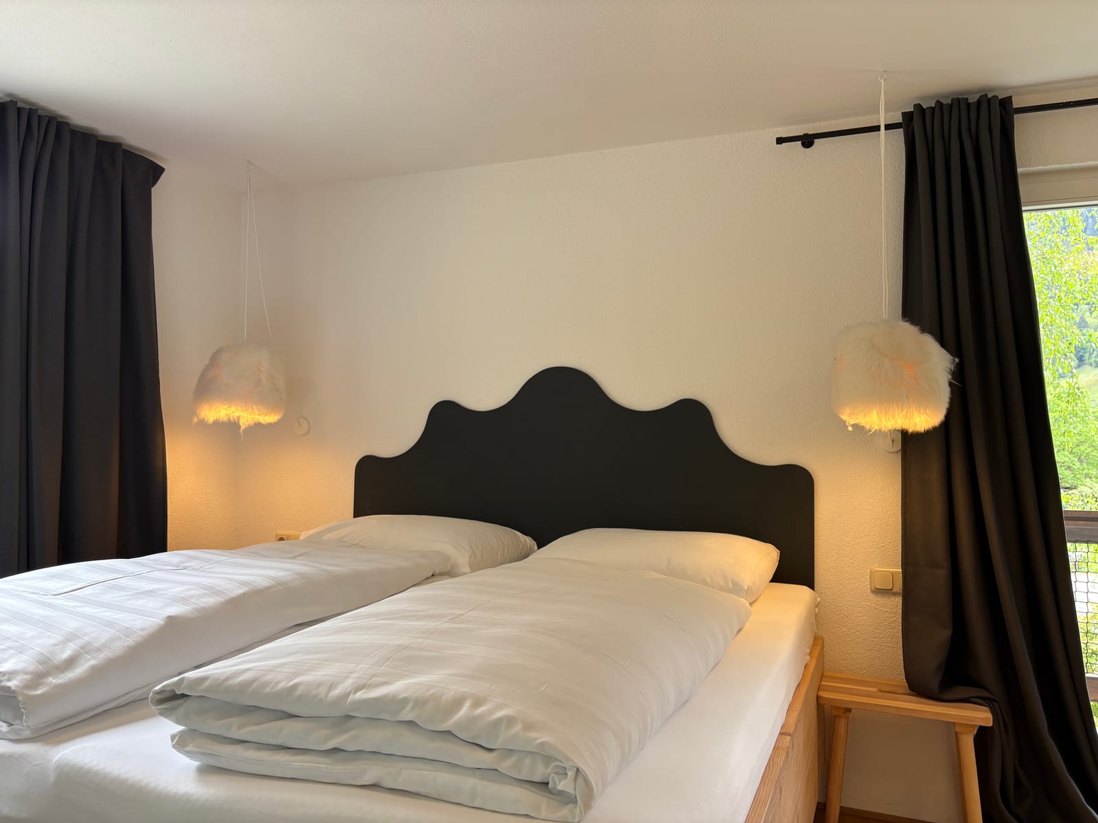 Doppelbett mit dunklem Kopfteil am Fenster – MONTAFONLodge