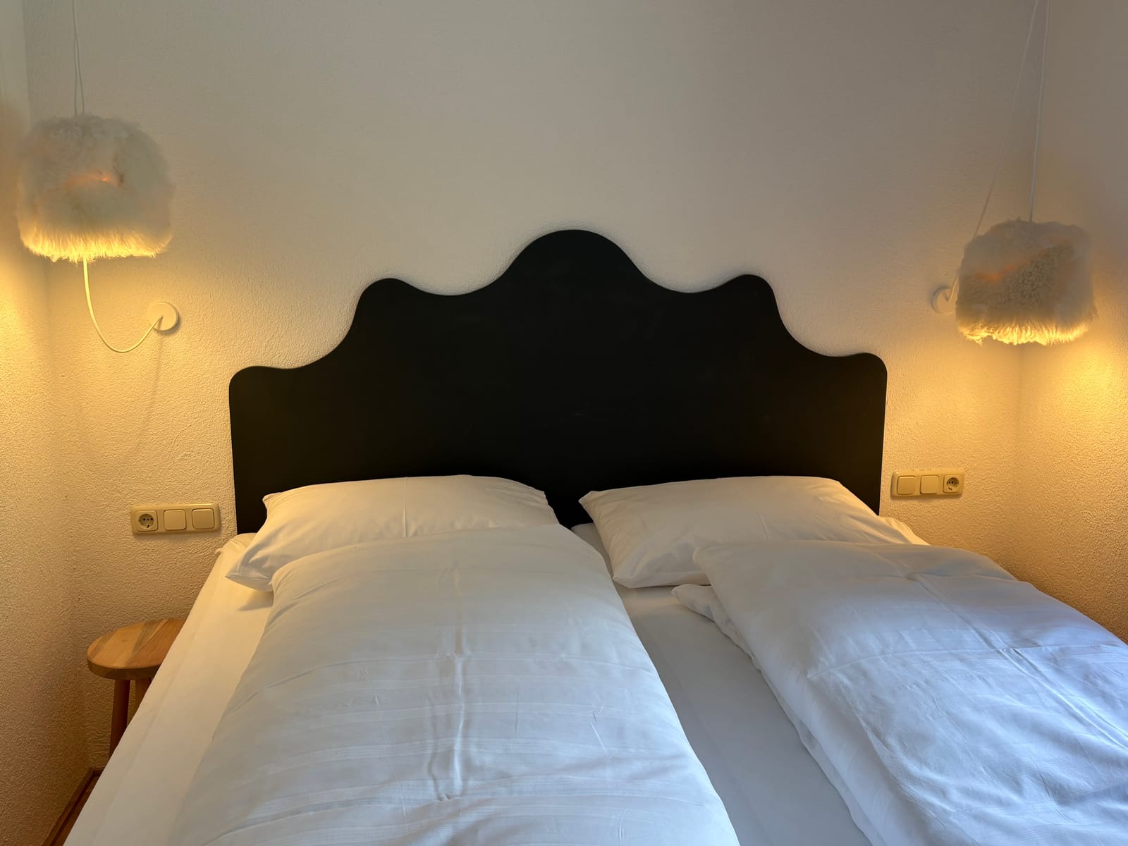 Doppelbett mit dunklem geschwungenem Kopfteil und Wandleuchten – MONTAFONLodge