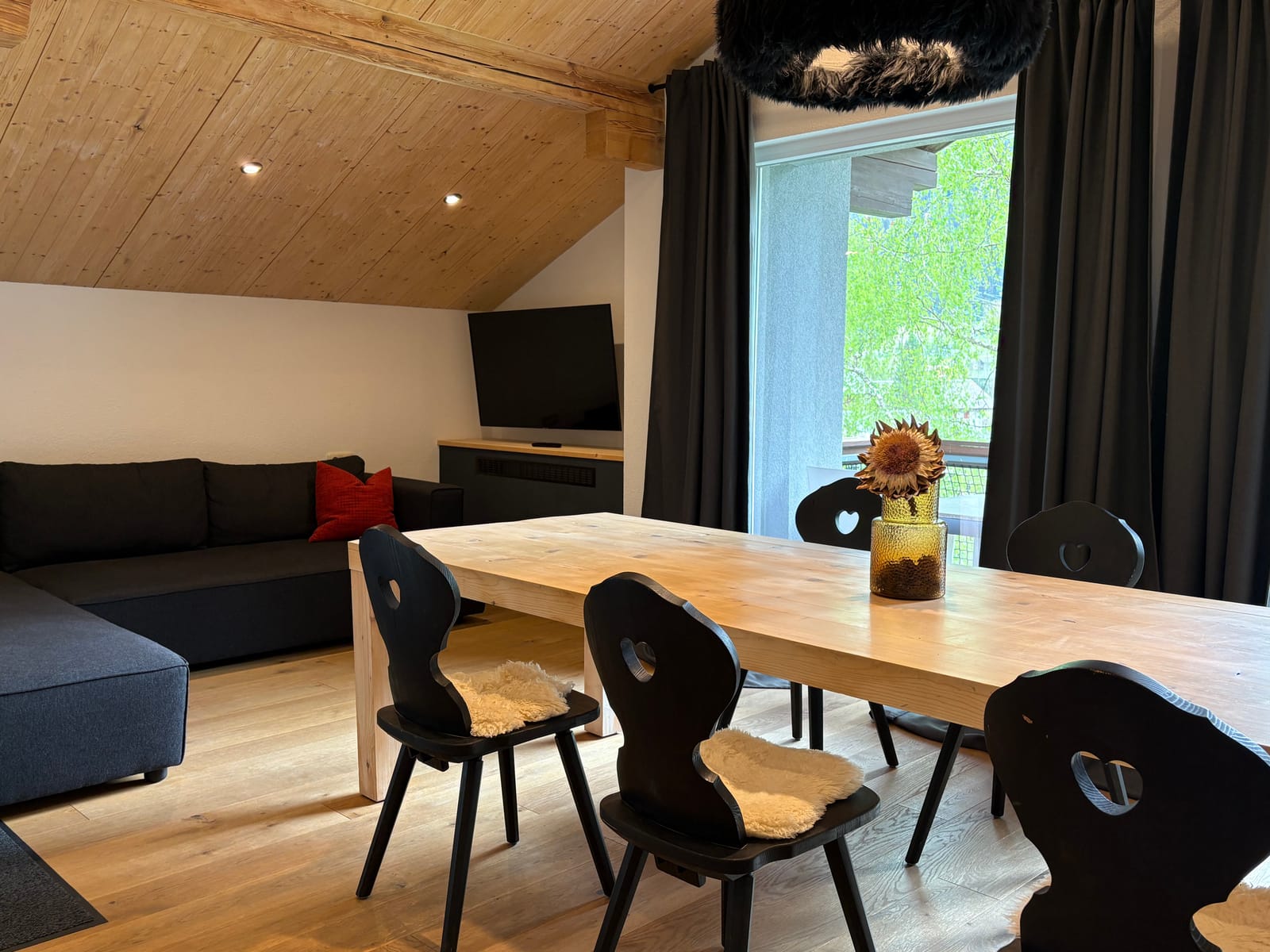 Essbereich mit Holztisch, Stühlen und Sofa am Fenster – MONTAFONLodge