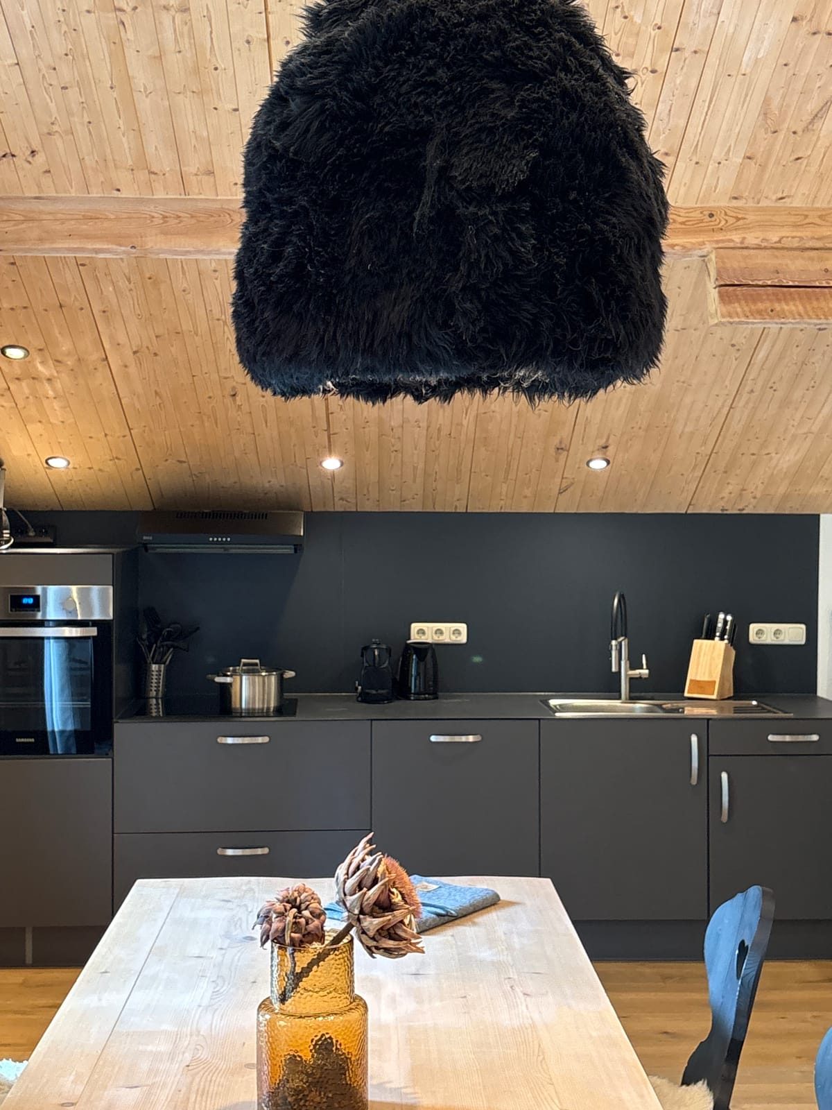 Dunkle Küchenzeile mit Essplatz und Fell-Deko an der Wand – MONTAFONLodge