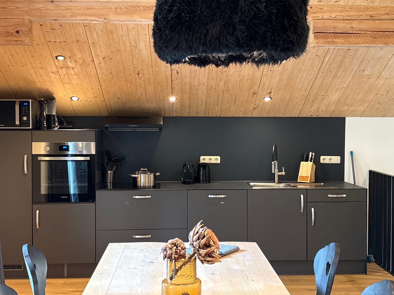 Dunkle Küchenzeile mit Esstisch und Fell-Deko – MONTAFONLodge
