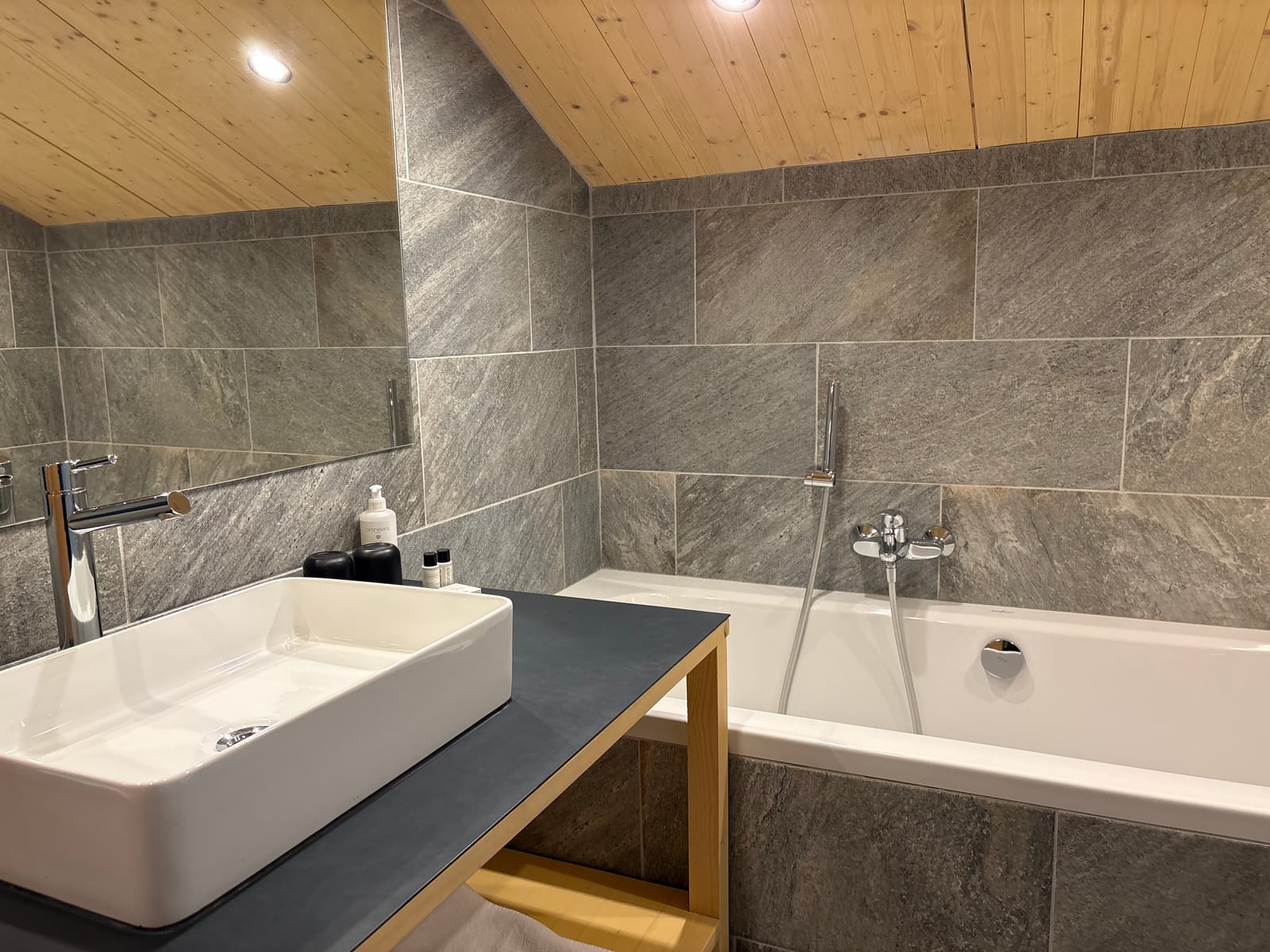 Bad mit Aufsatz-Waschbecken und Badewanne, Steinfliesen – MONTAFONLodge