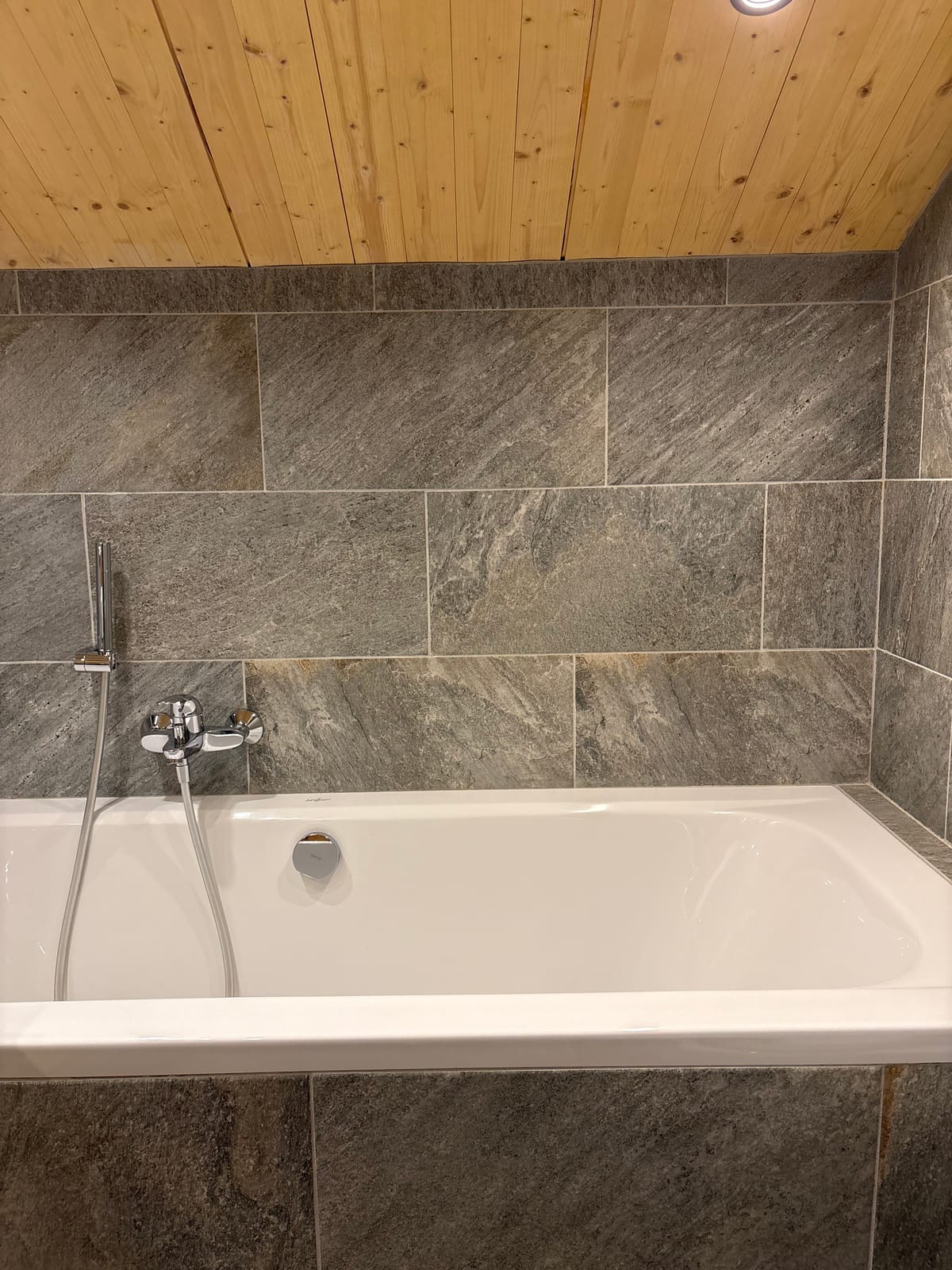Badewanne mit Wandarmatur, Steinfliesen – MONTAFONLodge