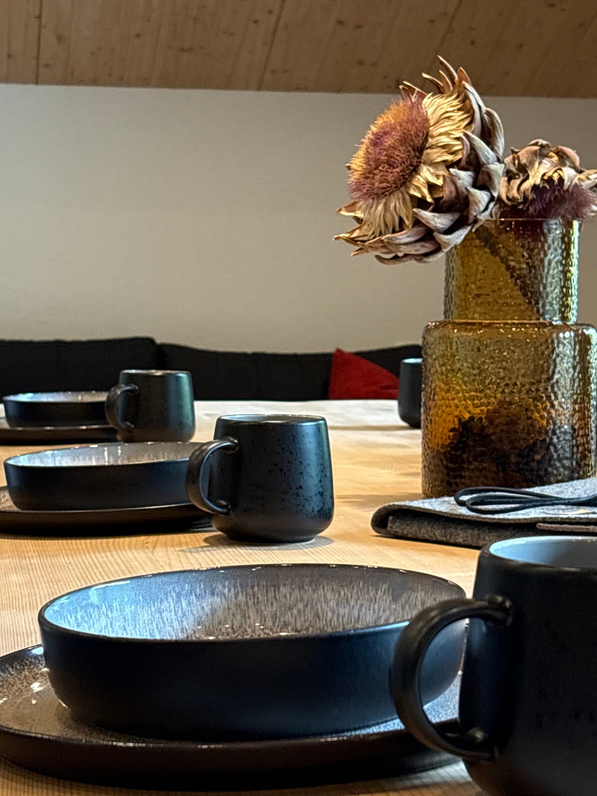 Gedeckter Tisch mit schwarzem Geschirr, Deko-Blumen und Sofa – MONTAFONLodge