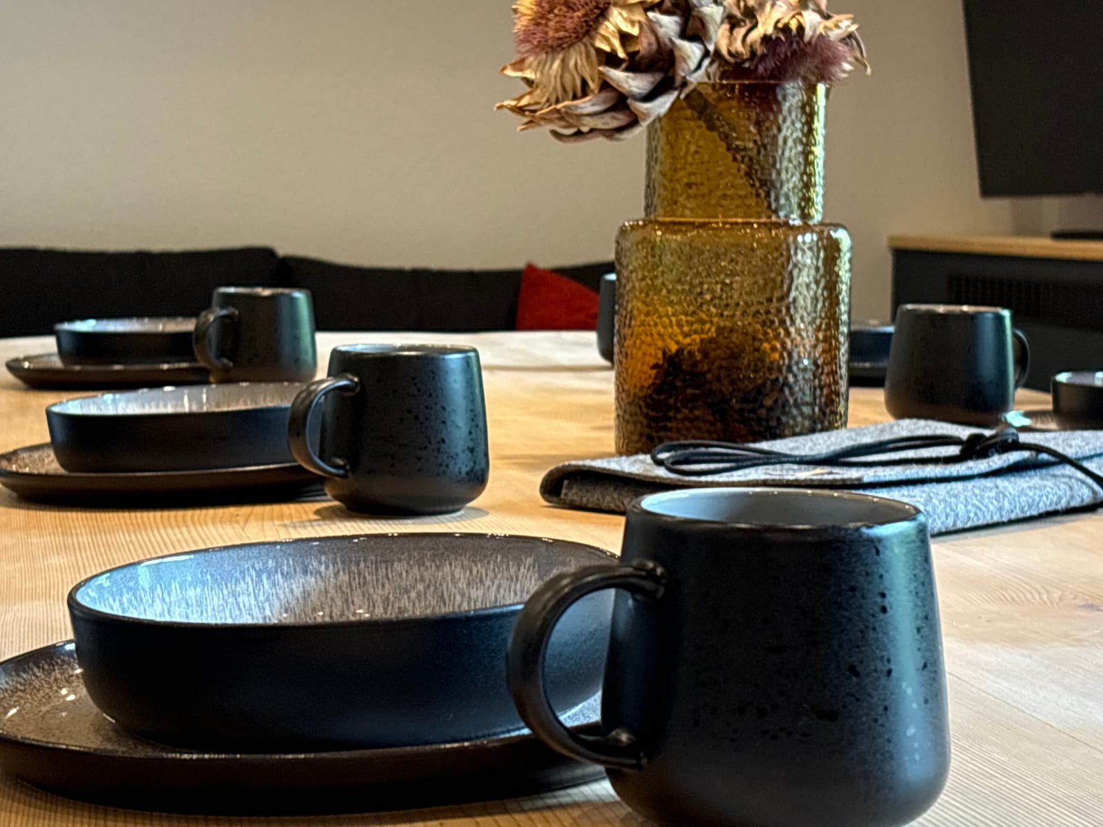 Gedeckter Tisch mit schwarzem Geschirr und Deko-Blumen – MONTAFONLodge