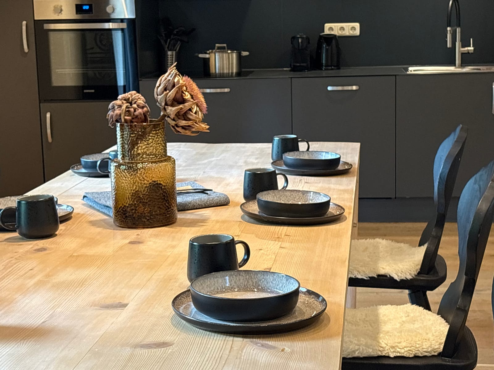 Gedeckter Tisch mit schwarzem Geschirr vor der Küche – MONTAFONLodge