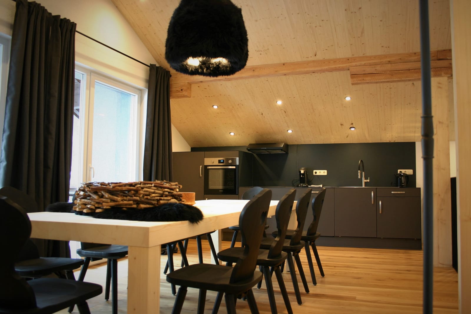 Essplatz mit Tisch und Stühlen, offene Küche und Pendelleuchte – MONTAFONLodge