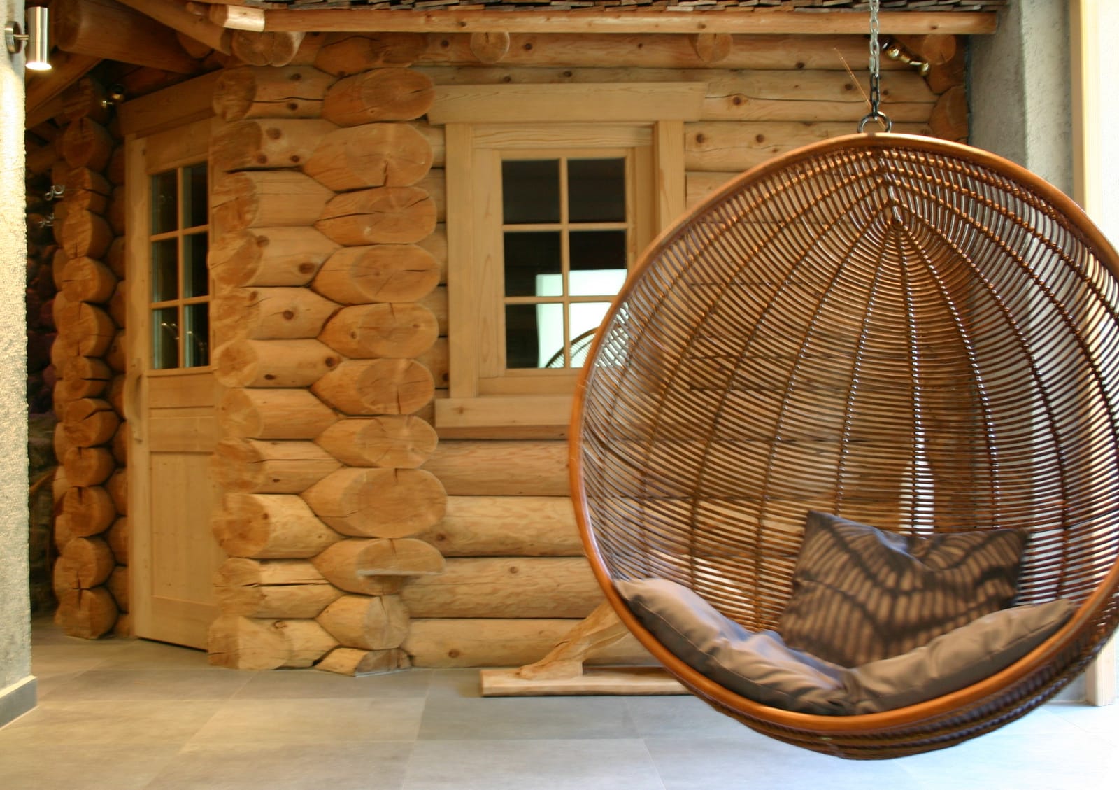 Blockhaus-Sauna mit Rattan-Hängesessel am Fenster – MONTAFONLodge