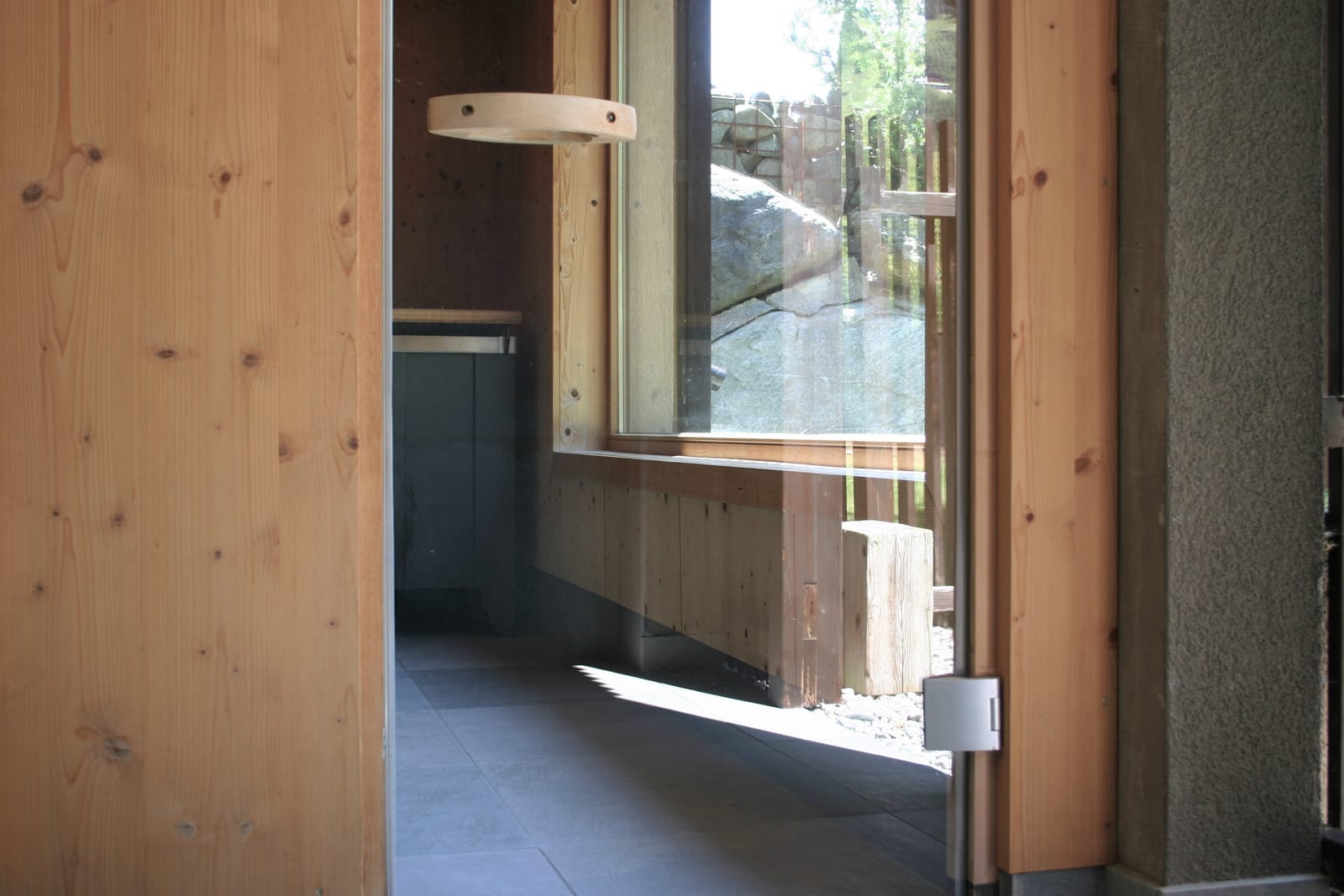 Sauna-Vorraum mit Glastür und Blick nach draußen – MONTAFONLodge