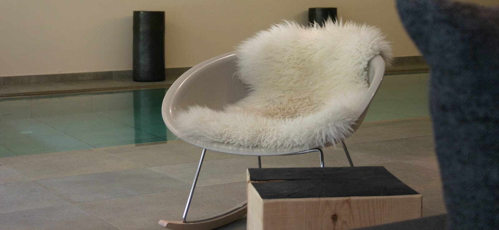 Designer-Sessel mit weißem Schaffell am Pool – MONTAFONLodge