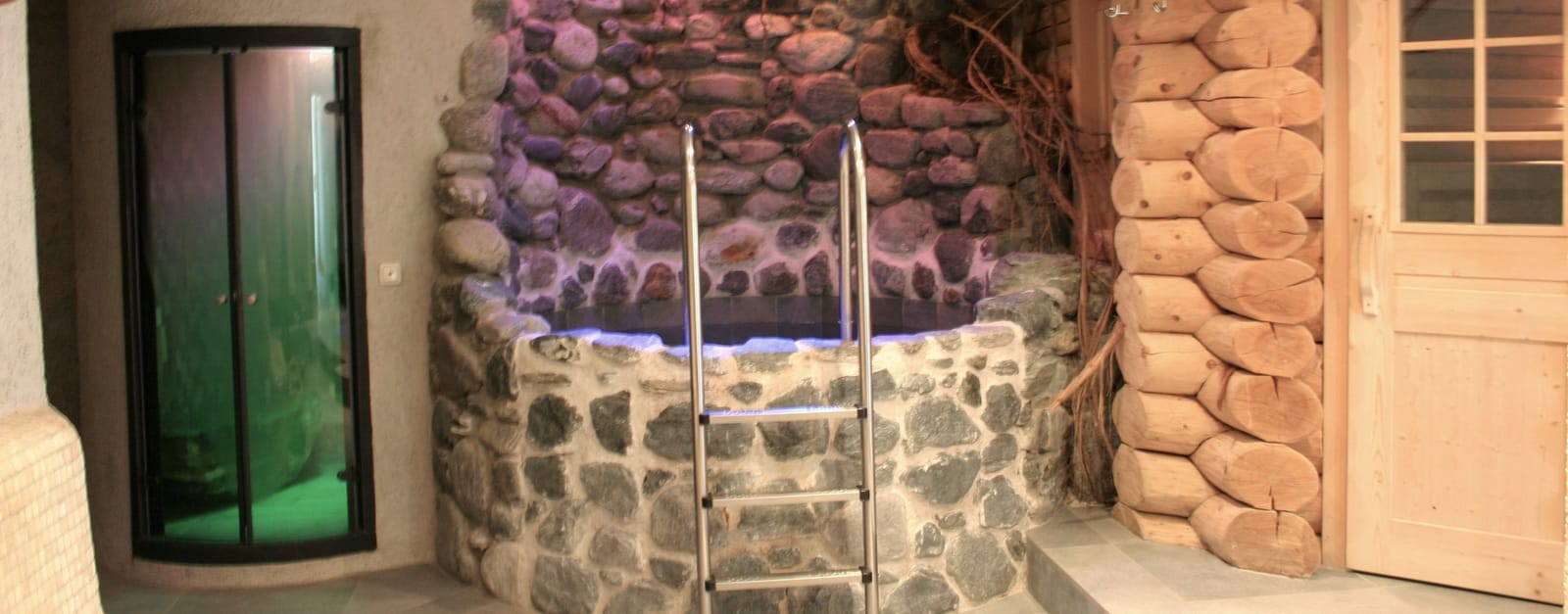 Stein-Whirlpool mit Edelstahlleiter und Natursteinmauer – MONTAFONLodge