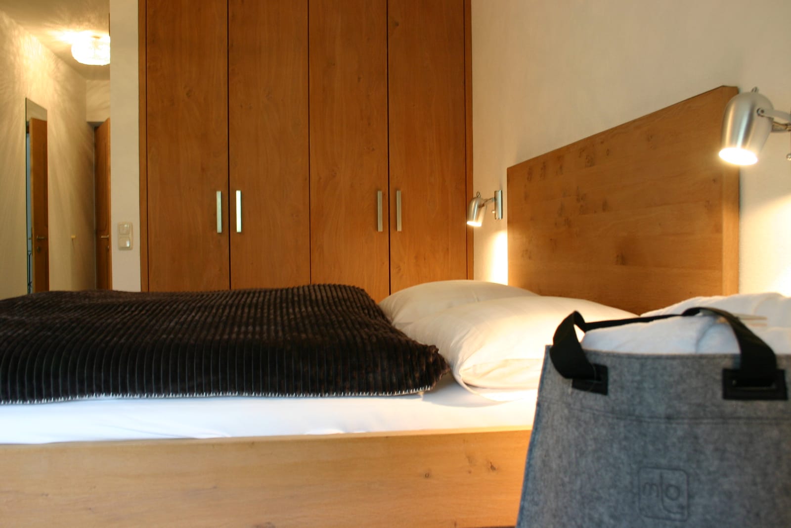 Doppelbett mit Holz-Schrankwand und Zirben-Kopfteil, Filztasche – MONTAFONLodge