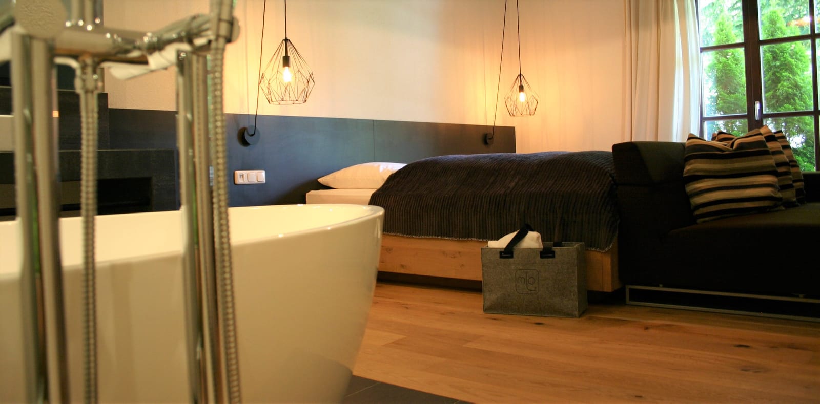 Doppelzimmer mit freistehender Badewanne neben dem Bett, Pendelleuchten – MONTAFONLodge