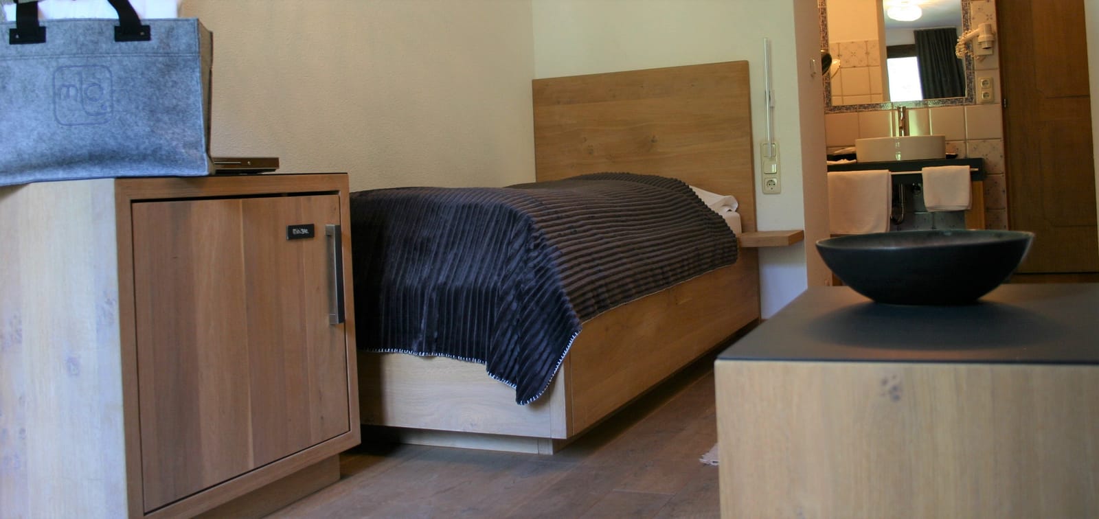 Einzelbett mit blauer Kordsamtdecke, Holz-Kopfteil und seitlichem Schrank – MONTAFONLodge