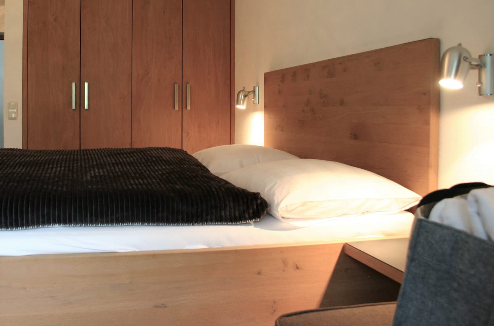 Doppelbett mit Holz-Schrankwand, Zirben-Kopfteil und Wandleuchte – MONTAFONLodge