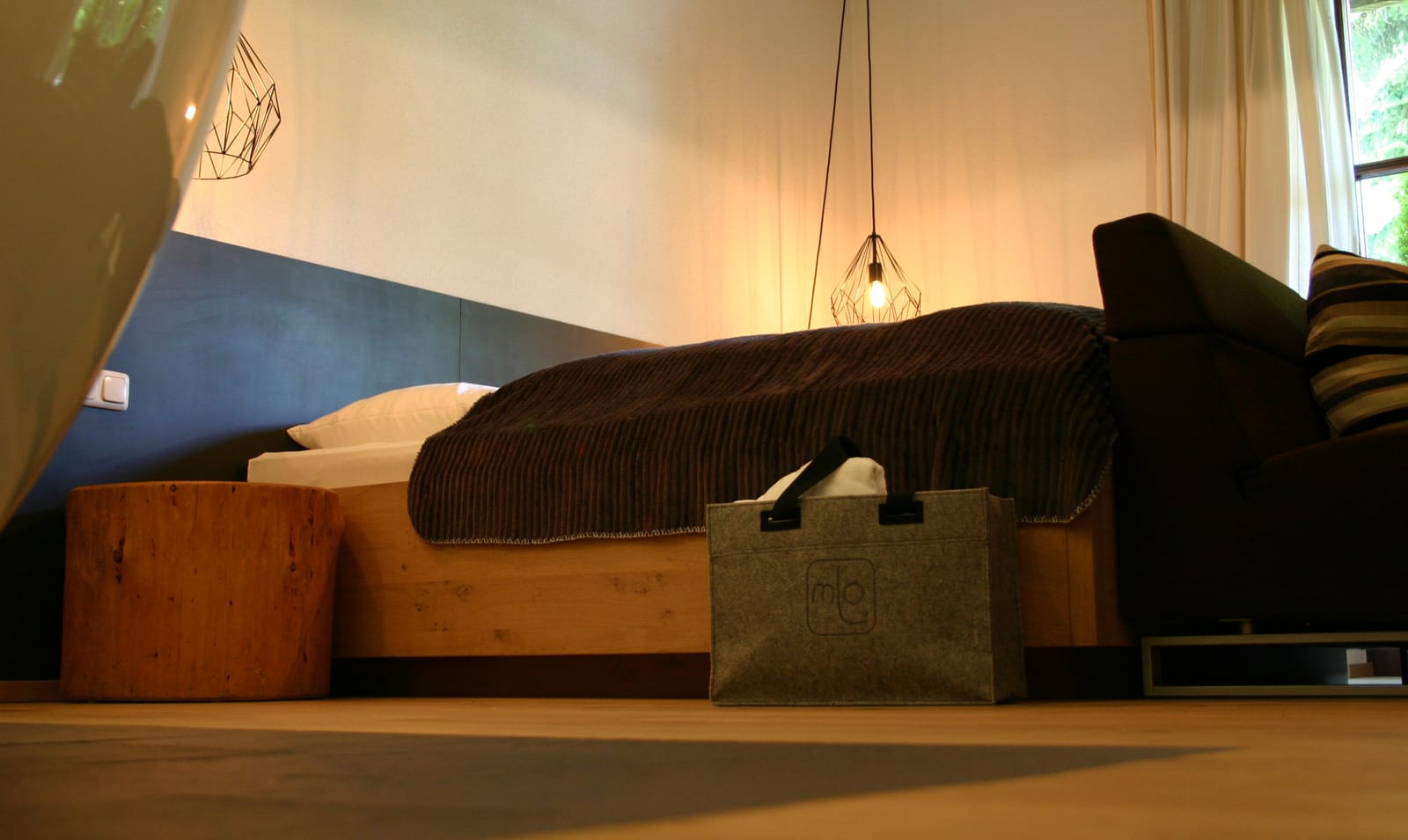 Doppelbett mit dunkler Kordsamtdecke und Deko-Filztasche – MONTAFONLodge