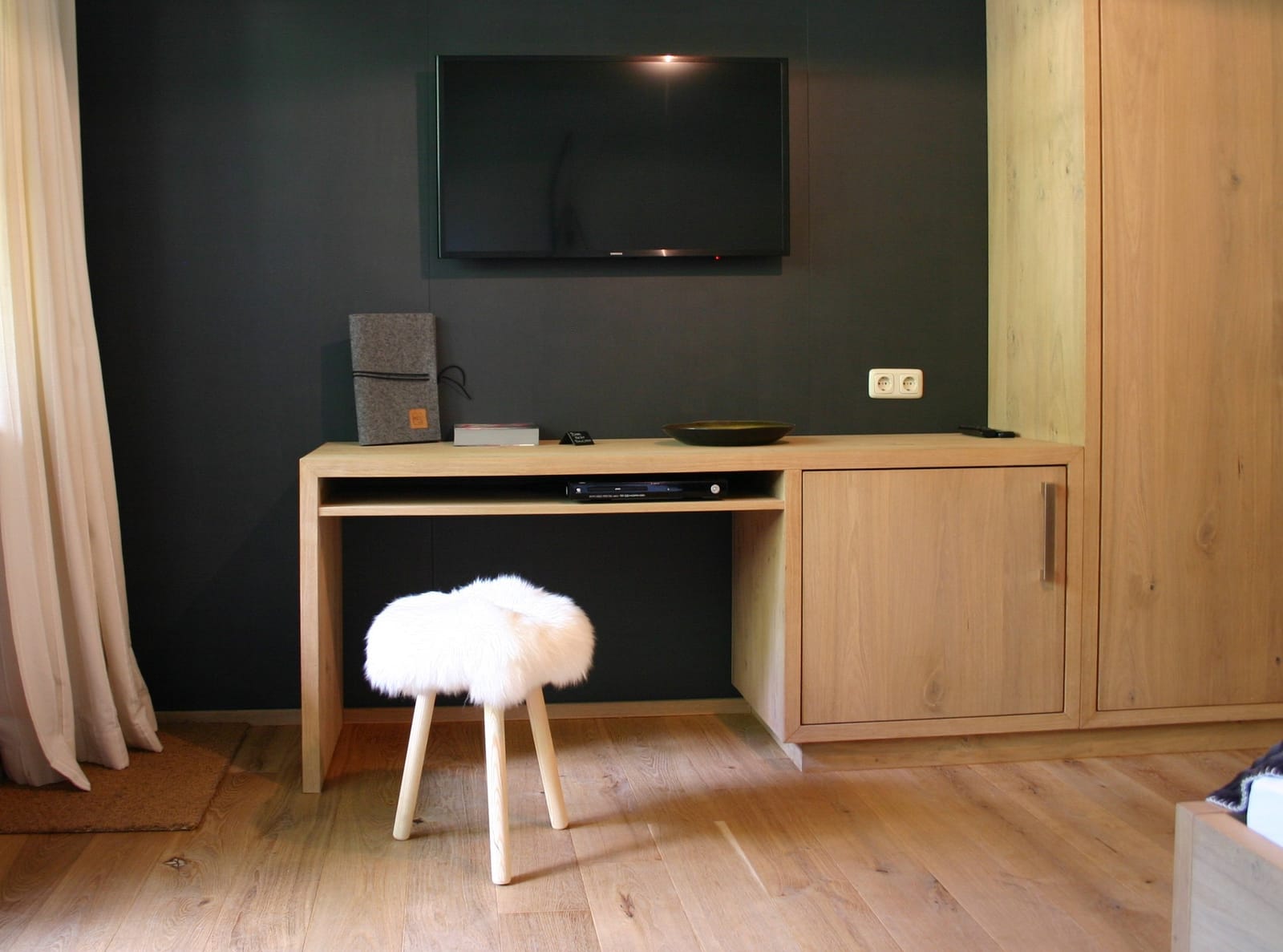 Wand-TV über Schreibtisch mit Schaffell-Hocker – MONTAFONLodge