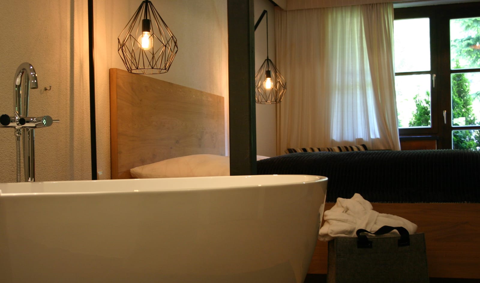 Freistehende Badewanne mit Bademantel, Bett und Fenster – MONTAFONLodge