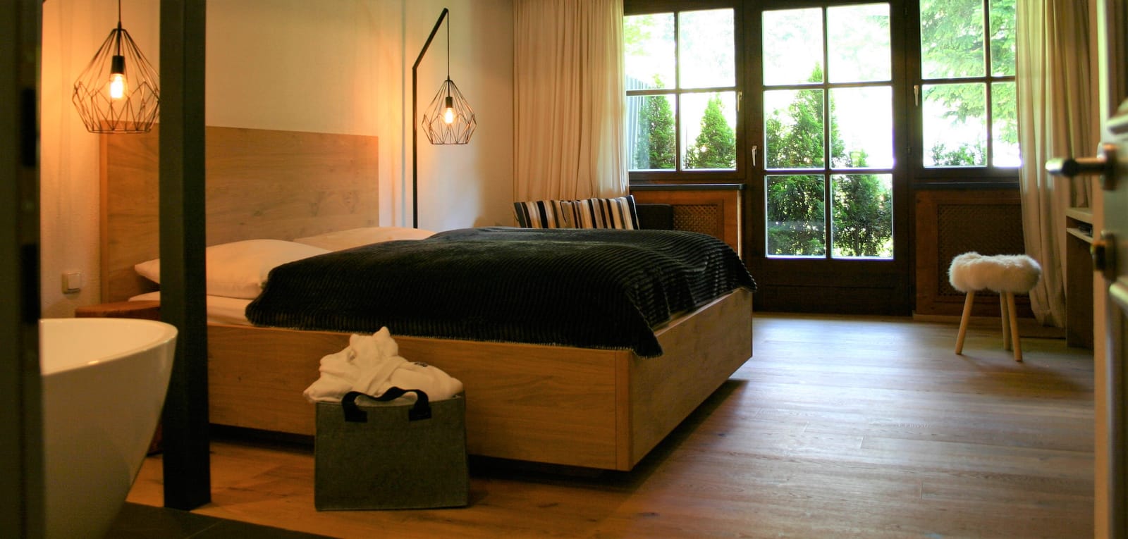 Doppelbett am Fenster mit Deko-Tasche auf Holzboden – MONTAFONLodge