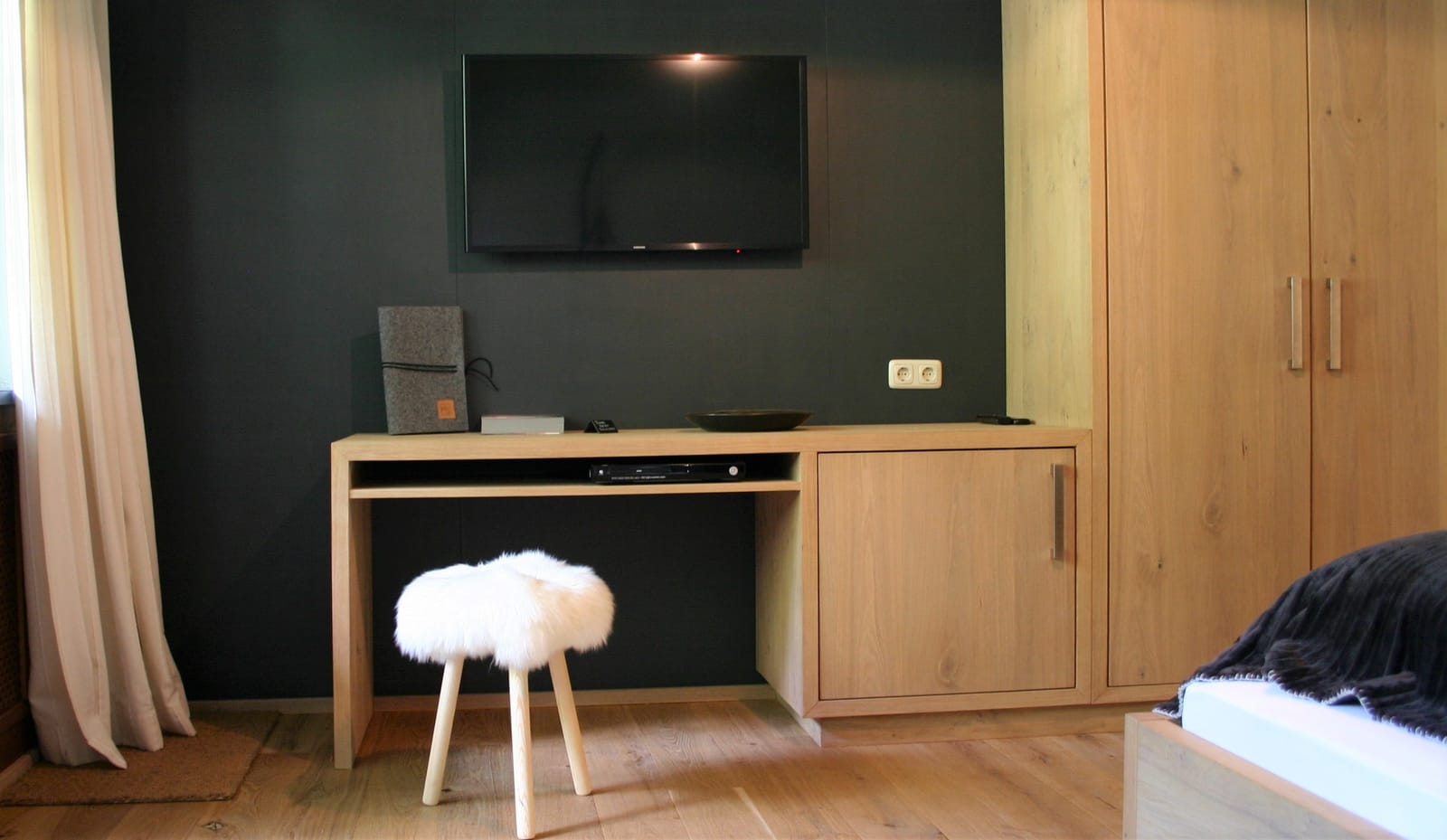 Wand-TV über Schreibtisch mit Schaffell-Hocker – MONTAFONLodge